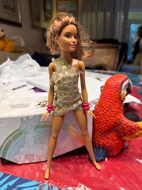 Barbie doll wearing a sparkly, gold sequined, one-shoulder dress and pink bangle